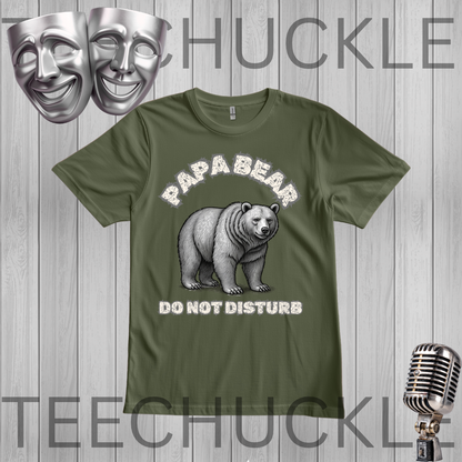 A green graphic t-shirt featuring a cartoon mama bear and the text 'MAMA BEAR DO NOT DISTURB' in white. The t-shirt is displayed on a gray wood-plank background , a vintage microphone, and comedy/tragedy masks in the corners.