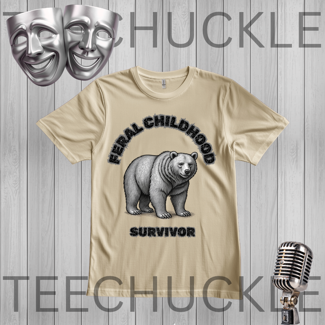 A sand graphic t-shirt featuring a black and white illustration of a grizzly bear with the text 'FERAL CHILDHOOD SURVIVOR' on the front. The t-shirt is displayed on a gray wood-plank background with a ' theatrical mask and vintage microphone props.