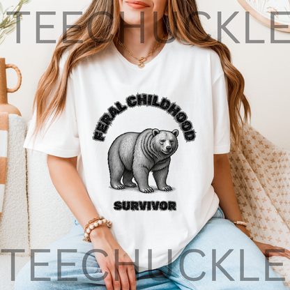 A woman wearing a white graphic T-shirt with a black bear illustration and the words 'FERAL CHILDHOOD SURVIVOR' printed on the front, seated indoors on a patterned couch.