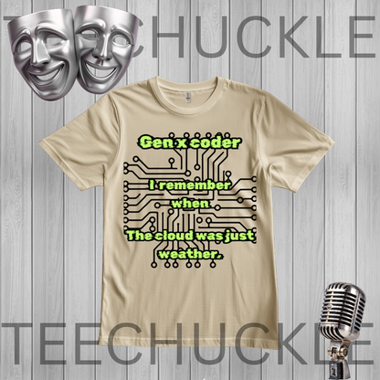 A sand graphic t-shirt displayed on a gray wood plank background, featuring a black circuit board design with green text that reads 'Gen x coder I remember when The cloud was just weather.' Silver comedy masks and a vintage microphone are shown as decorative props