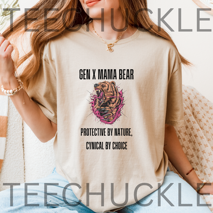A woman wearing a beige graphic t-shirt with a 'Gen X Mama Bear' print featuring a bear illustration and text, set against a cozy indoor background with a blanket.