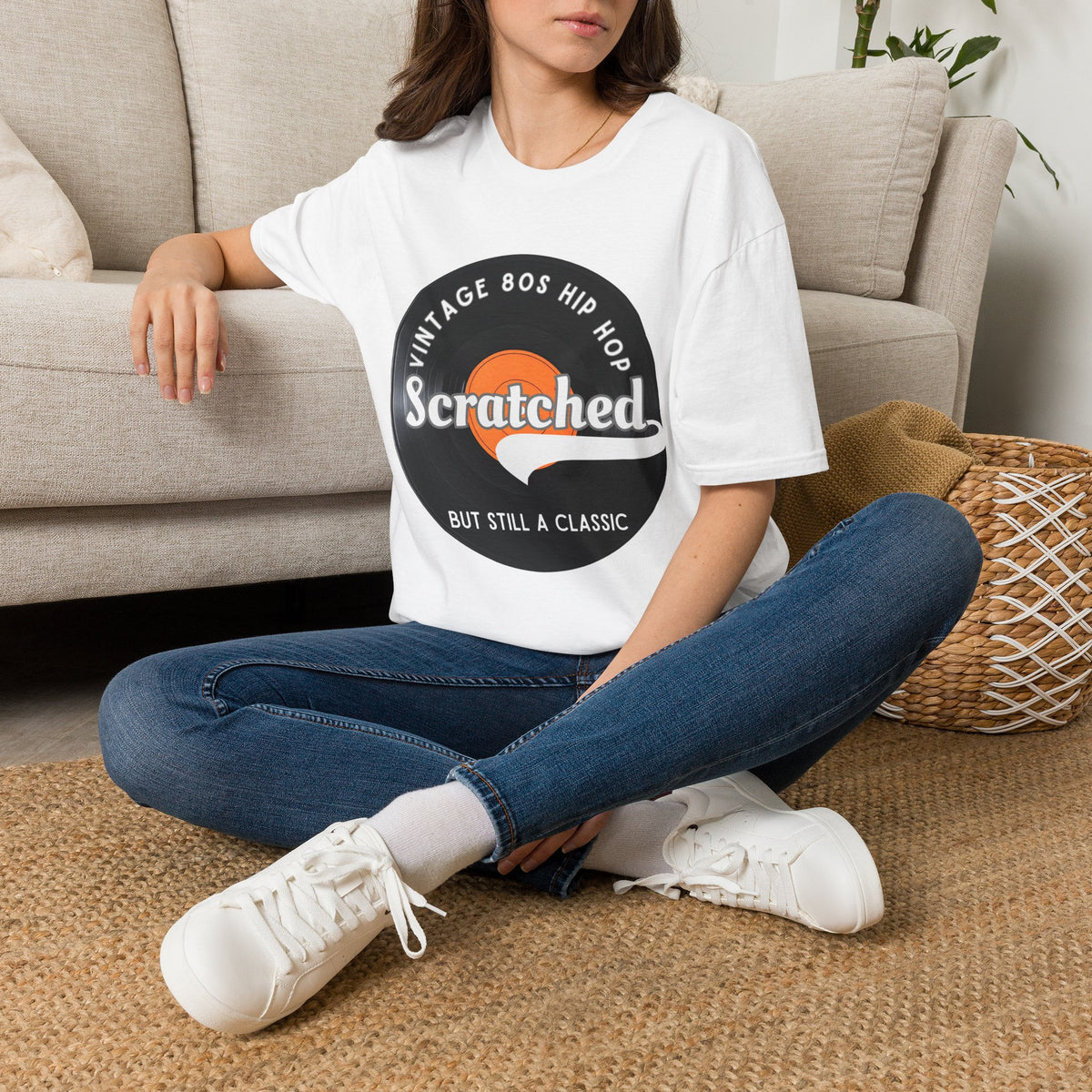 A white short-sleeve graphic T-shirtfeaturing a circular black-and-orange print that reads 'Vintage 80s Hip Hop' and 'Scratched But Still A Classic.'
