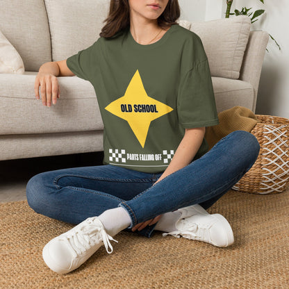 A woman sitting cross-legged on a woven rug in front of a beige sofa, wearing a green graphic T-shirt with a large yellow star and the text 'OLD SCHOOL' and 'PARTS FALLING OFF'.