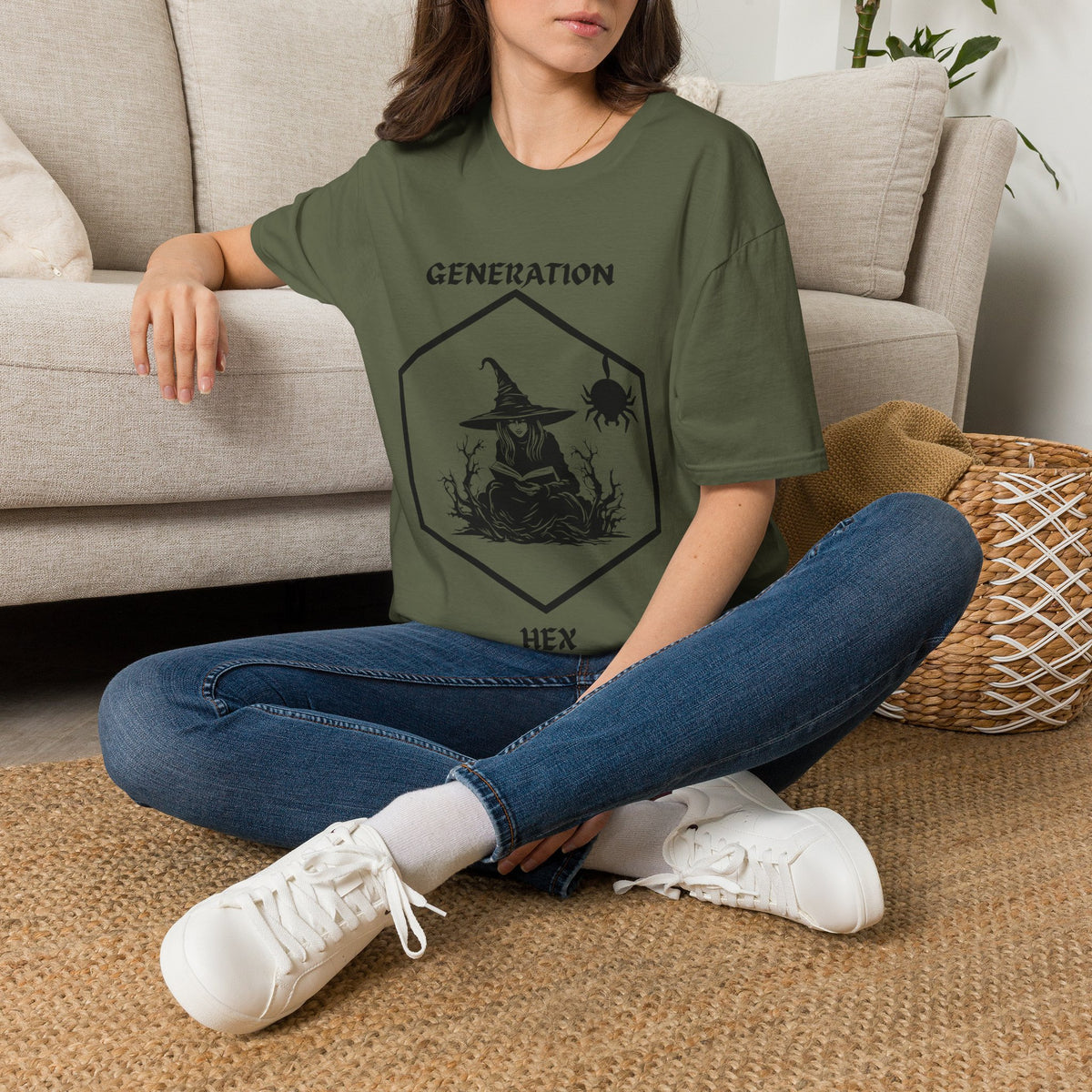 Person wearing a green t-shirt with a witch graphic, and the text "GENERATION HEX" sitting on the floor in a living room.