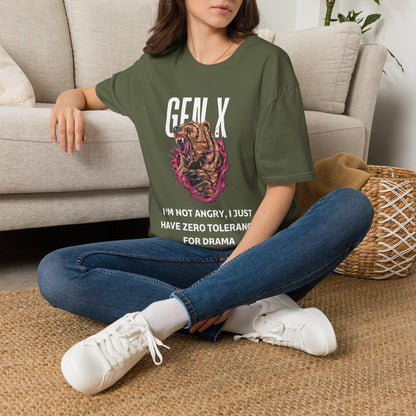 A woman sitting cross-legged on a woven rug in front of a beige sofa, wearing an green graphic T-shirt with  a roaring bear illustration with pink and black details, accompanied by the text 'GEN X' and 'PROTECTIVE BY NATURE, CYNICAL BY CHOICE'.  paired with blue jeans and white sneakers.